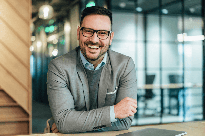 A smiling founder leaning on his desk